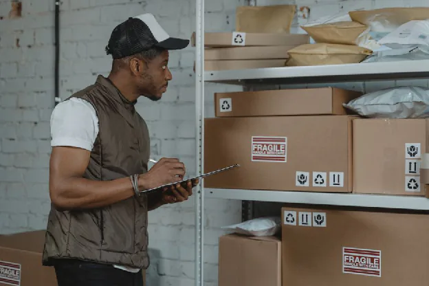 pre-shipment inspection - Courier checking packages in a warehouse, ensuring fragile handling