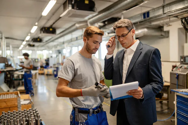 Two men at a factory reviewing a contract manufacturing requirement document