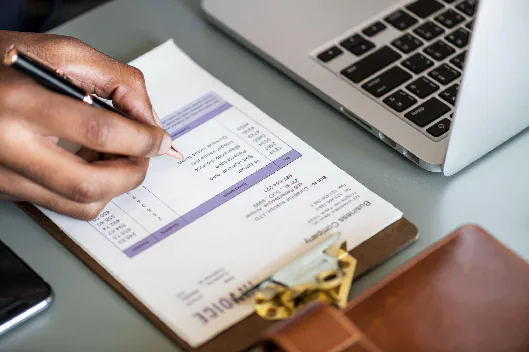 Close-up of a hand checking cost details on a supplier invoice during quote evaluation